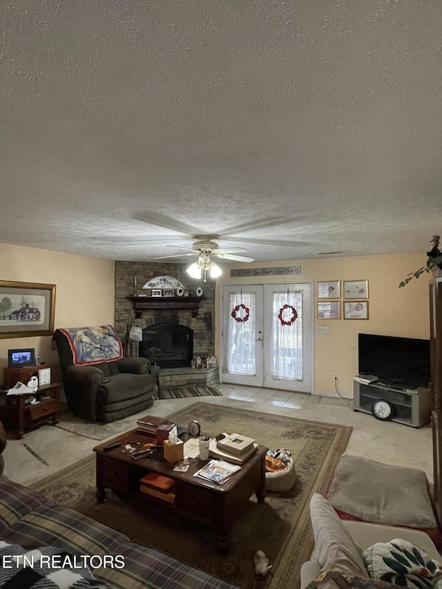 carpeted living room featuring ceiling fan, a stone fireplace, a textured ceiling, and french doors