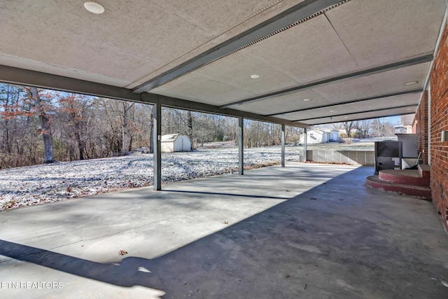 snow covered patio featuring a storage unit