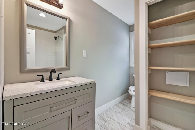 bathroom with toilet, vanity, and tiled shower