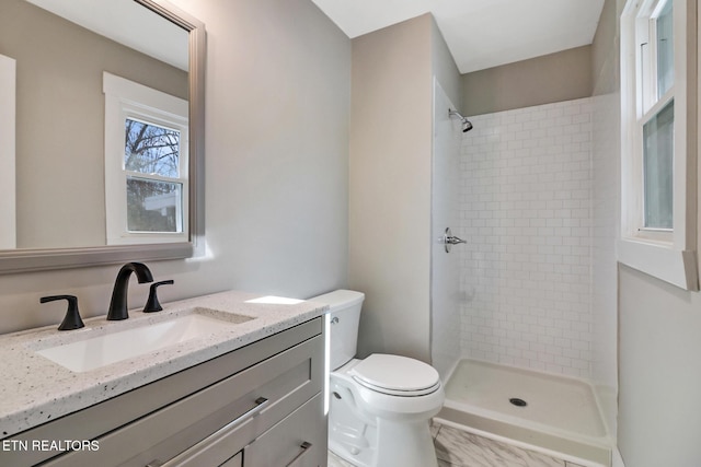 bathroom with tiled shower, vanity, and toilet