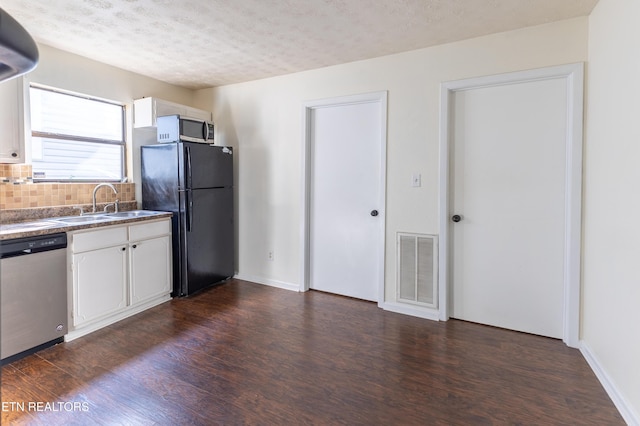 kitchen featuring sink, dark wood-type flooring, appliances with stainless steel finishes, white cabinetry, and a textured ceiling