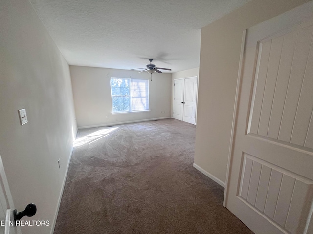 carpeted empty room featuring ceiling fan and a textured ceiling