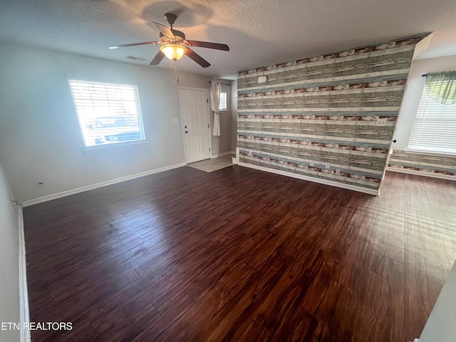 spare room featuring ceiling fan, dark wood-type flooring, and a textured ceiling