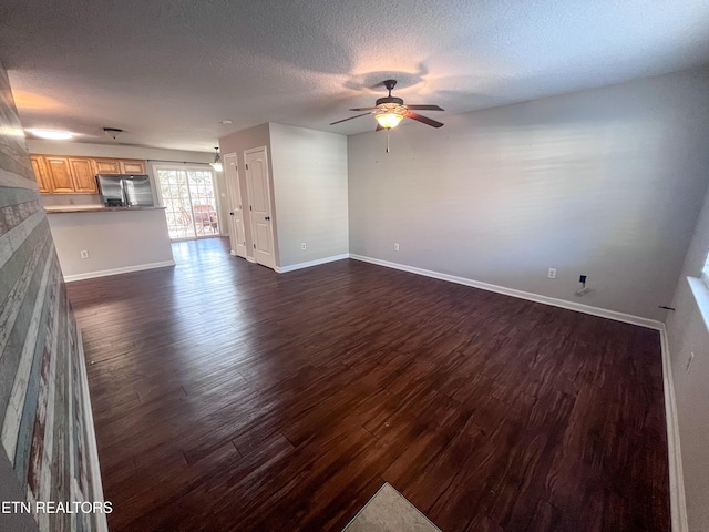 unfurnished living room featuring dark wood-type flooring, a textured ceiling, and ceiling fan