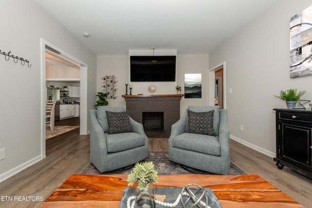 living room featuring a brick fireplace and hardwood / wood-style floors