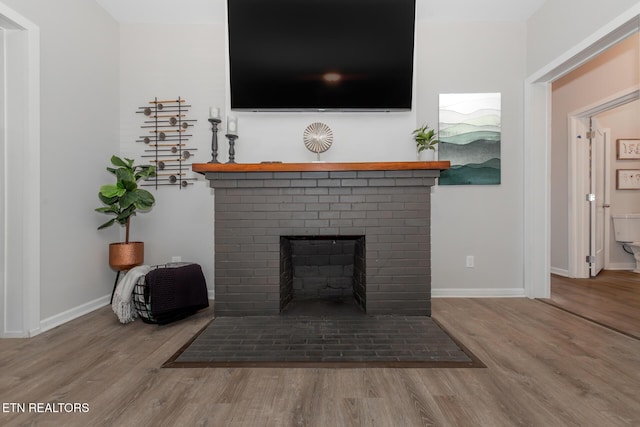 interior details featuring a brick fireplace and wood-type flooring