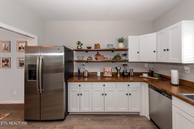 kitchen featuring sink, hardwood / wood-style flooring, appliances with stainless steel finishes, white cabinetry, and wood counters