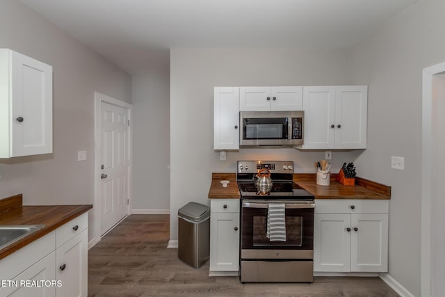 kitchen featuring butcher block counters, white cabinetry, light wood-type flooring, and appliances with stainless steel finishes