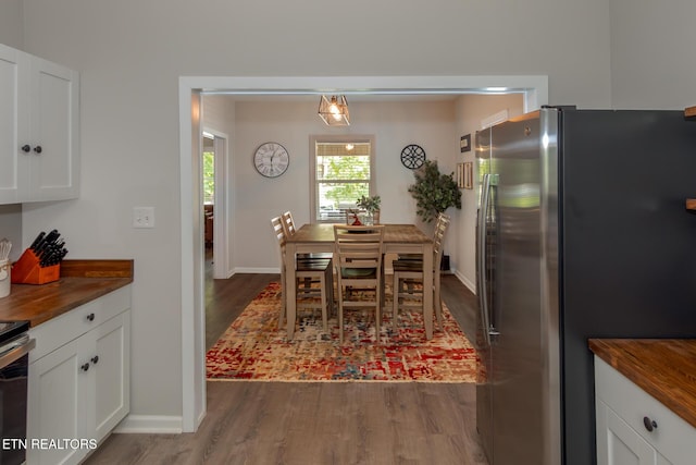 kitchen with white cabinets, butcher block counters, stainless steel fridge, and dark hardwood / wood-style flooring