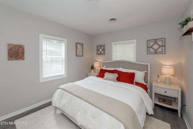 bedroom featuring multiple windows and dark hardwood / wood-style floors