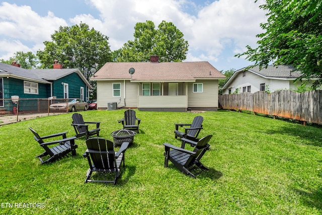 rear view of property featuring central AC, a yard, and a fire pit