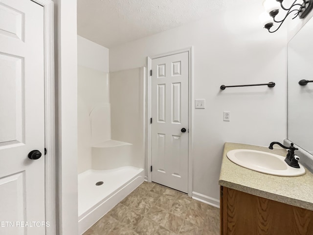 bathroom featuring a textured ceiling, walk in shower, and vanity