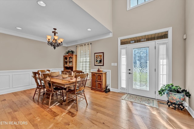 dining space with a notable chandelier, ornamental molding, and light hardwood / wood-style floors