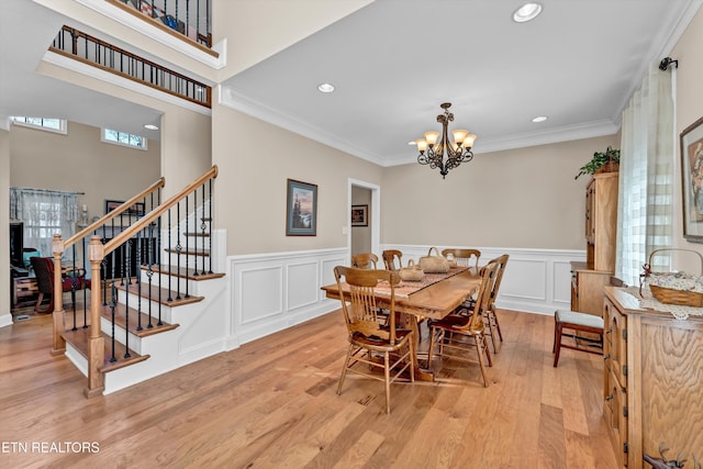 dining space featuring crown molding, an inviting chandelier, and light wood-type flooring