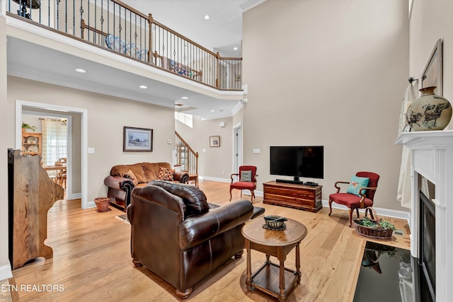 living room featuring a high ceiling, crown molding, and light hardwood / wood-style flooring