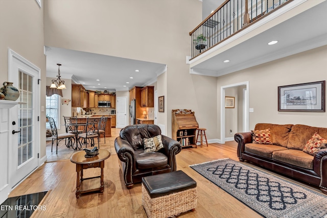 living room featuring ornamental molding, light hardwood / wood-style flooring, and a notable chandelier