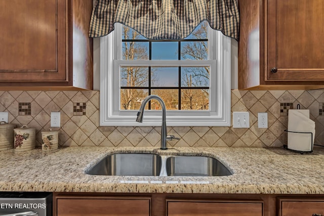 kitchen featuring tasteful backsplash, light stone countertops, sink, and dishwasher