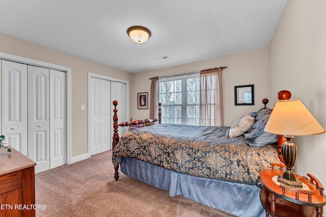 bedroom with multiple closets, carpet flooring, and a textured ceiling