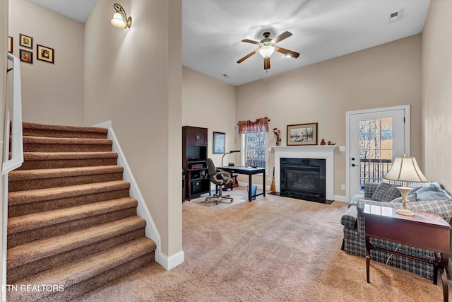 living room featuring ceiling fan, a towering ceiling, and carpet floors