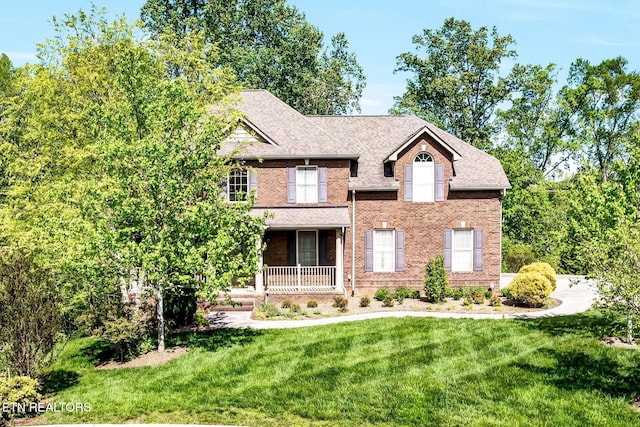 view of front of house featuring a porch, a front lawn, and brick siding