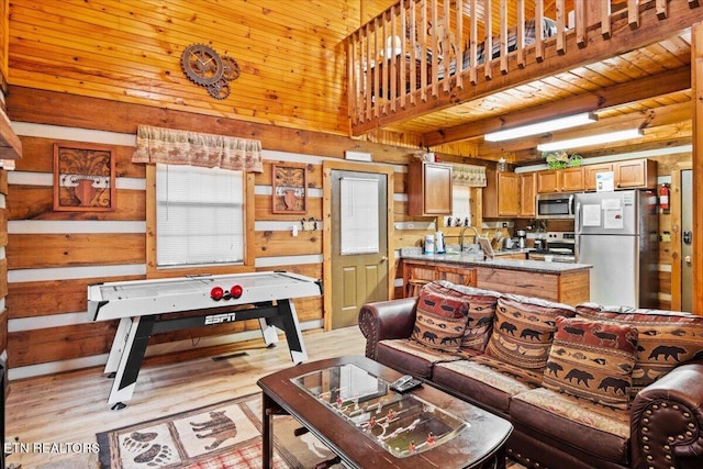 living room featuring sink, wood walls, wood ceiling, light wood-type flooring, and beam ceiling