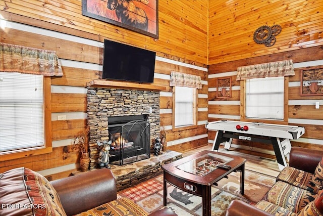 living room featuring a stone fireplace, a towering ceiling, and wood walls