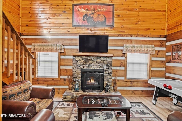 living room with a healthy amount of sunlight, a fireplace, a high ceiling, and wood walls