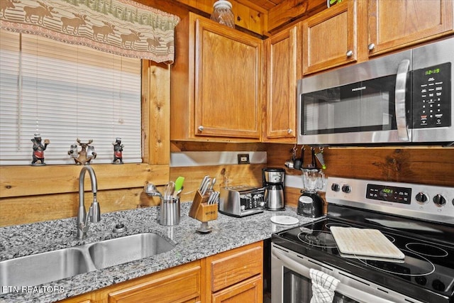 kitchen with light stone counters, appliances with stainless steel finishes, and sink