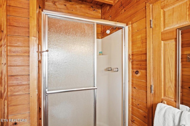 bathroom featuring wooden walls and a shower with shower door