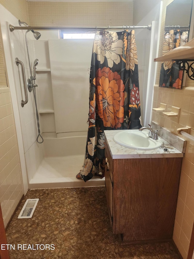 bathroom with walk in shower, vanity, and tile walls