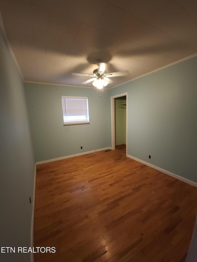 empty room featuring wood-type flooring, ornamental molding, and ceiling fan