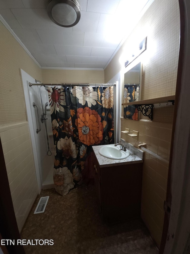 bathroom with vanity, tile walls, crown molding, and walk in shower