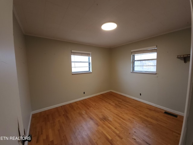 unfurnished room featuring ornamental molding, a healthy amount of sunlight, and light hardwood / wood-style floors