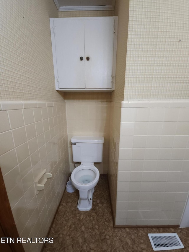 bathroom featuring tile walls and toilet