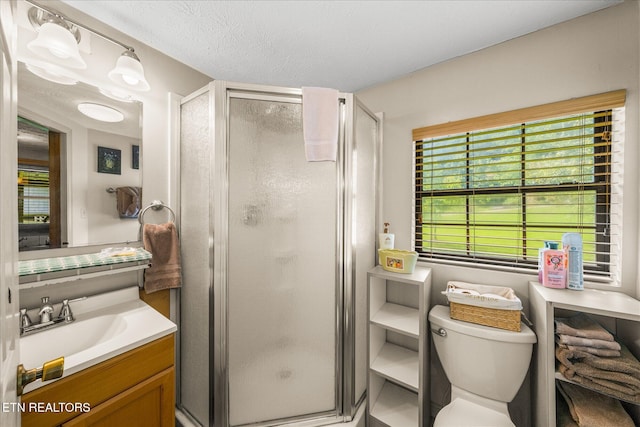 bathroom featuring vanity, toilet, a textured ceiling, and walk in shower