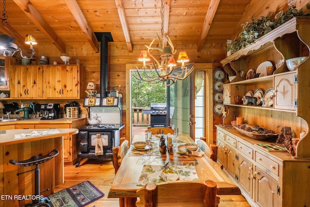 dining area featuring wood walls, wood ceiling, vaulted ceiling with beams, light hardwood / wood-style flooring, and a wood stove