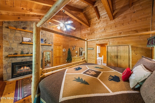 bedroom featuring a stone fireplace, hardwood / wood-style floors, high vaulted ceiling, wooden ceiling, and beam ceiling