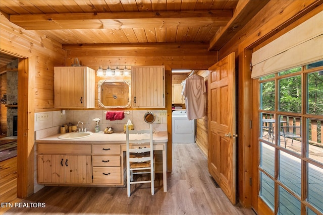 kitchen featuring washer / clothes dryer, wooden walls, sink, and beamed ceiling