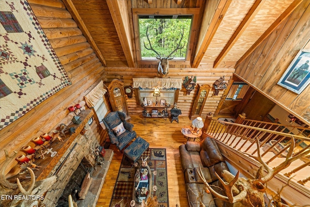 living room with lofted ceiling with beams, wood-type flooring, and rustic walls