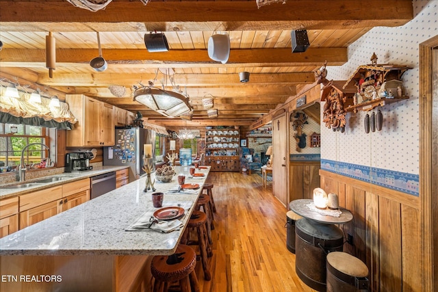 kitchen featuring sink, a kitchen island with sink, light hardwood / wood-style floors, wooden ceiling, and beam ceiling