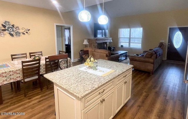 kitchen featuring decorative light fixtures, dark wood-type flooring, light stone countertops, and a kitchen island