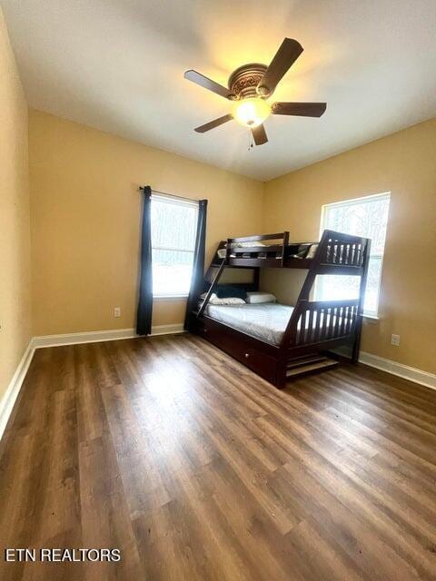 bedroom featuring ceiling fan, multiple windows, and dark hardwood / wood-style floors