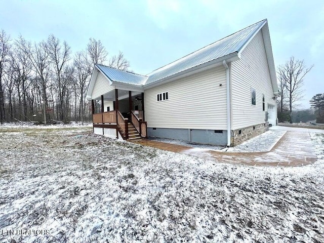 snow covered property featuring a porch and a garage