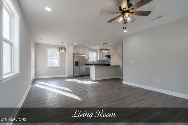 unfurnished living room featuring dark hardwood / wood-style flooring and ceiling fan