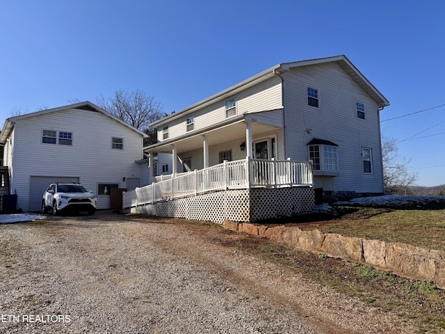 rear view of property with a garage and covered porch