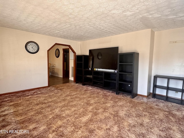 unfurnished living room with a textured ceiling and dark colored carpet