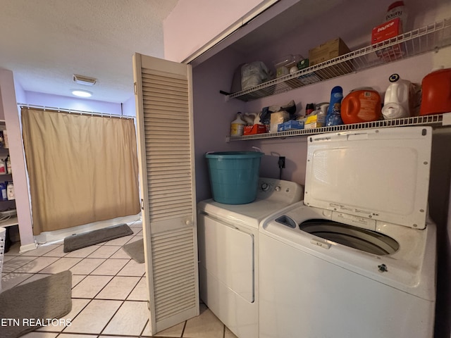 laundry area featuring independent washer and dryer, a textured ceiling, and light tile patterned floors