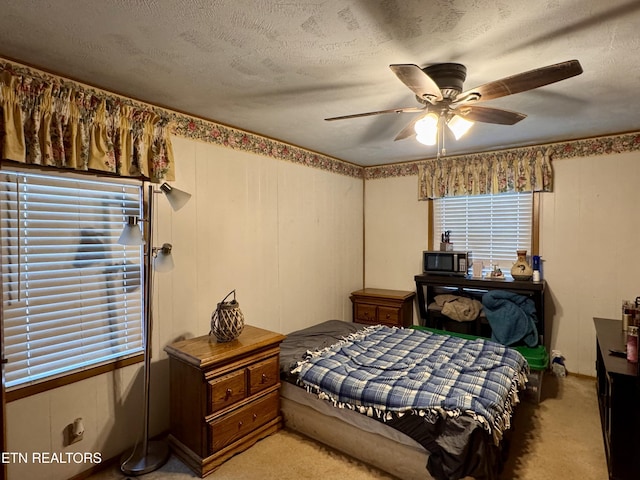 bedroom with light carpet, a textured ceiling, and ceiling fan