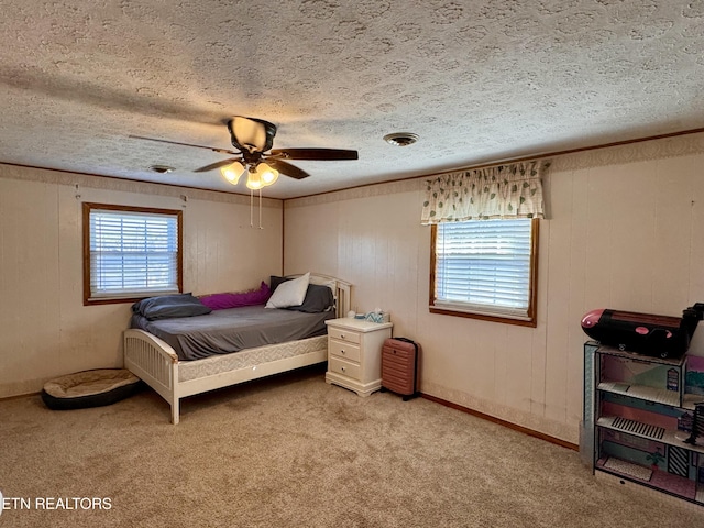 bedroom with multiple windows, a textured ceiling, light colored carpet, and ceiling fan