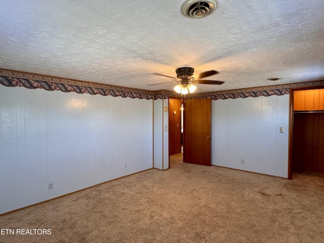 unfurnished bedroom featuring ceiling fan, light colored carpet, and a textured ceiling